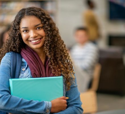 young female smiling and holding binder